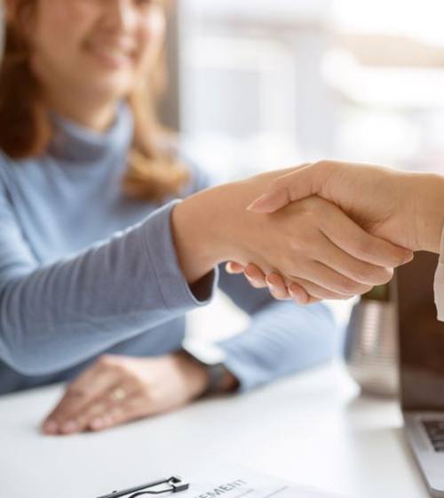 Two people shaking hands across desk