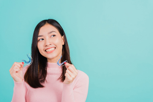 Woman smiling and holding a set of retainers