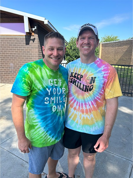 Two men smiling together in tie dye shirts