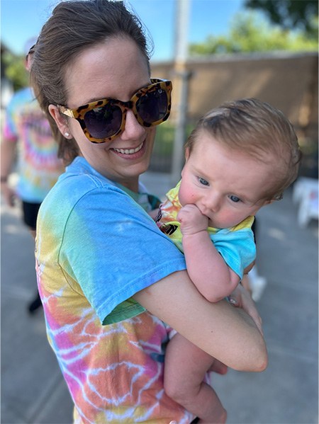 Doctor Hanson in a tie dye shirt holding her baby