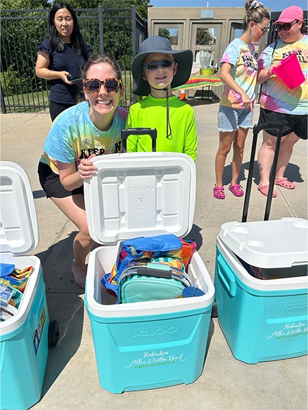 Doctor Hanson posing with a child in front of coolers full of supplies