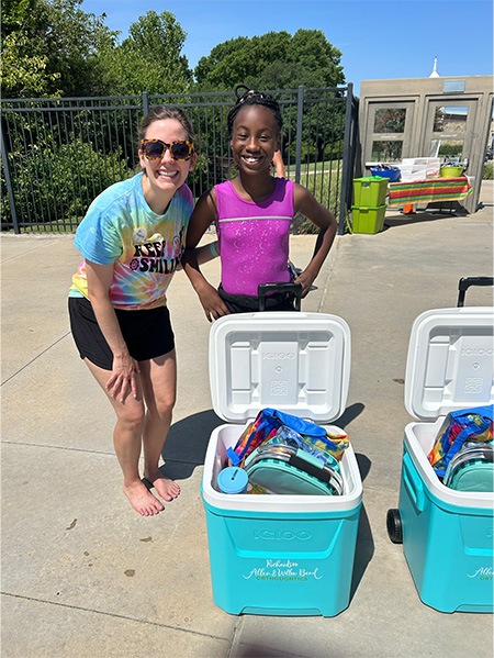 Doctor Hanson smiling with a young girl next to coolers