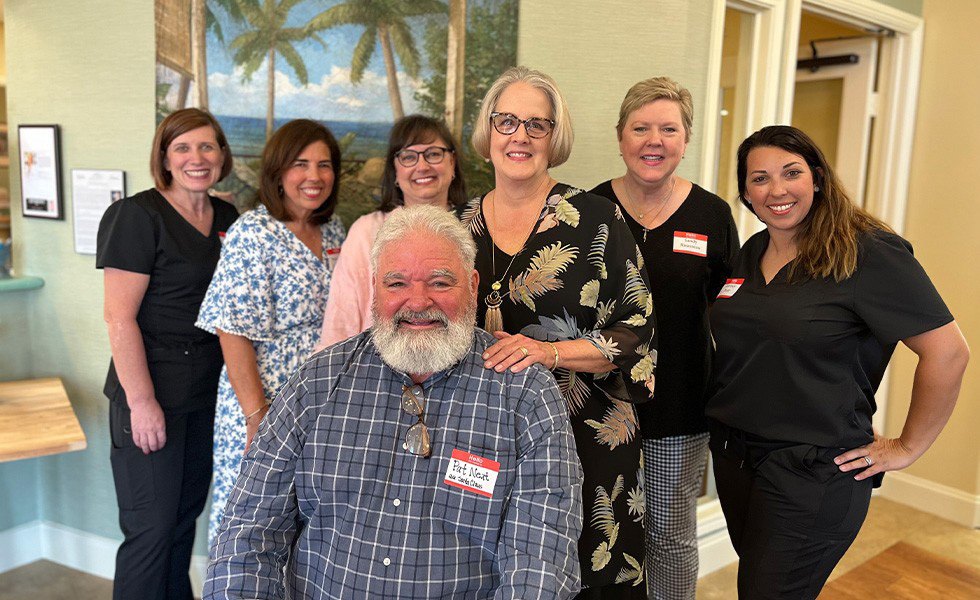 Orthodontic team members smiling with an elderly man in reception area