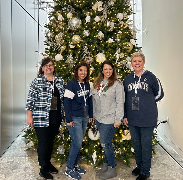 Four women smiling in front of Christmas tree