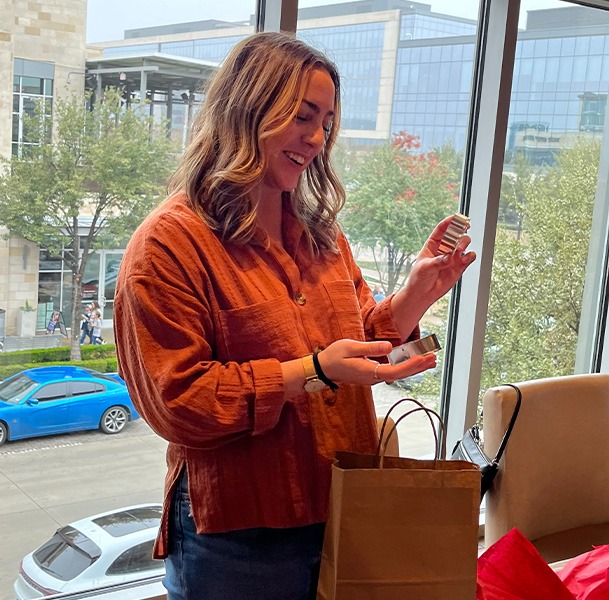 Woman opening gift with small bottles of perfume or makeup