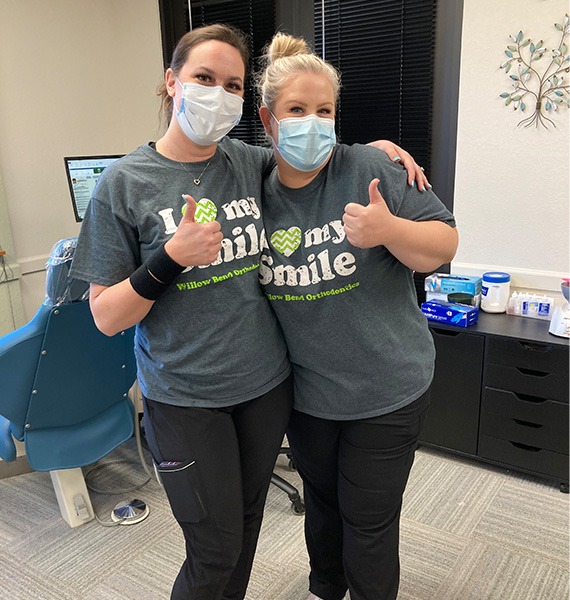 Two team members smiling and giving thumbs up while wearing masks