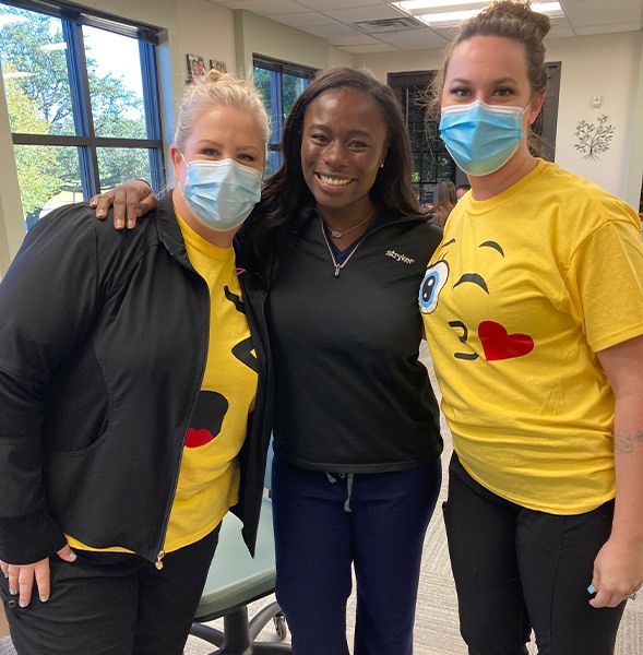 Three women smiling together at a community event