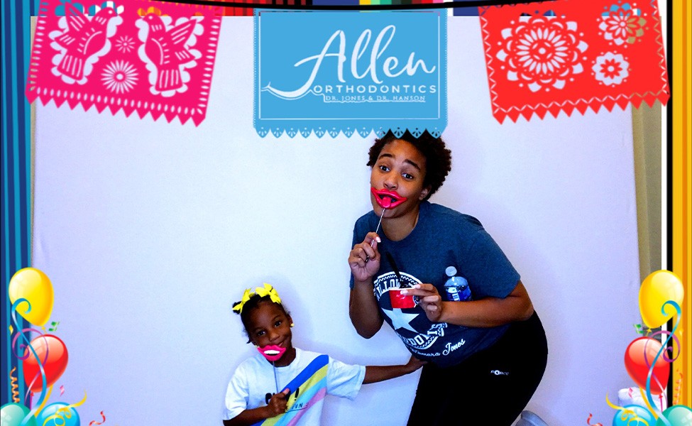 Woman and her young daughter holding props in a photo booth