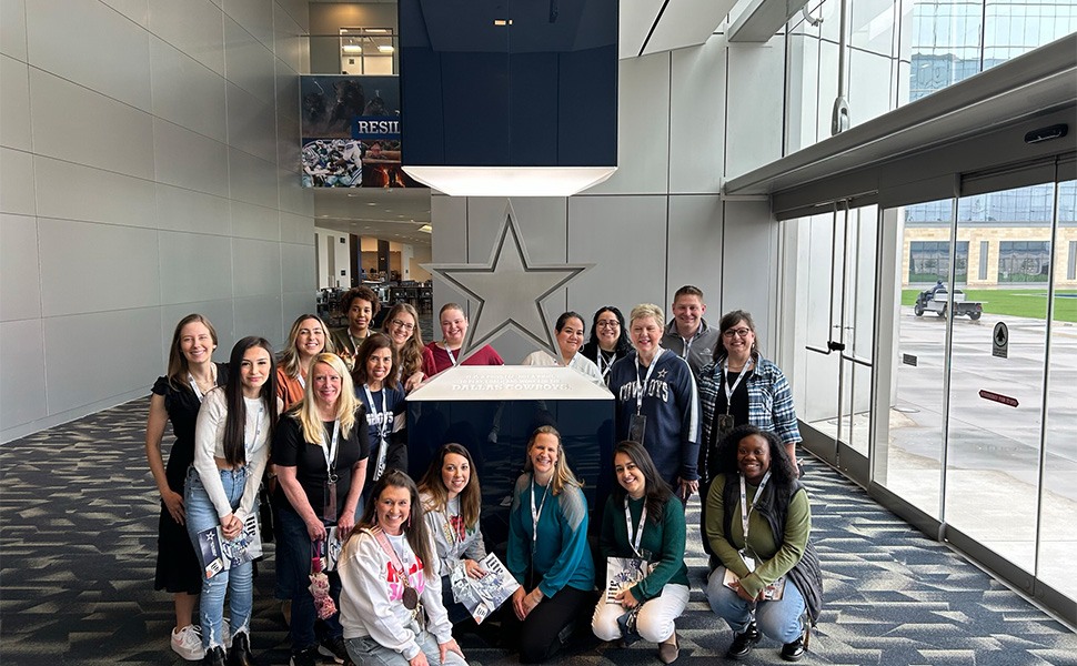 Orthodontic team posing with Dallas Cowboys star statue