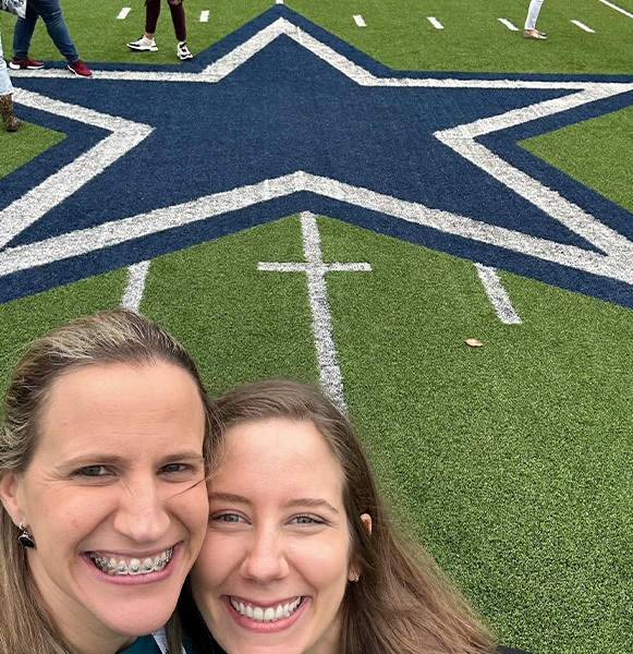 Two women taking selfie next to blue star on Dallas Cowboys field