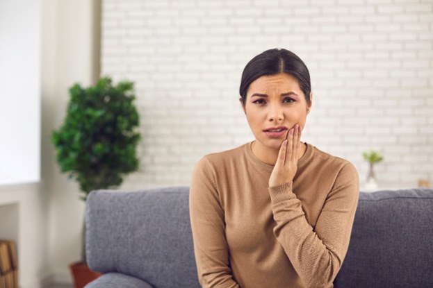 woman wincing and holding her jaw in pain