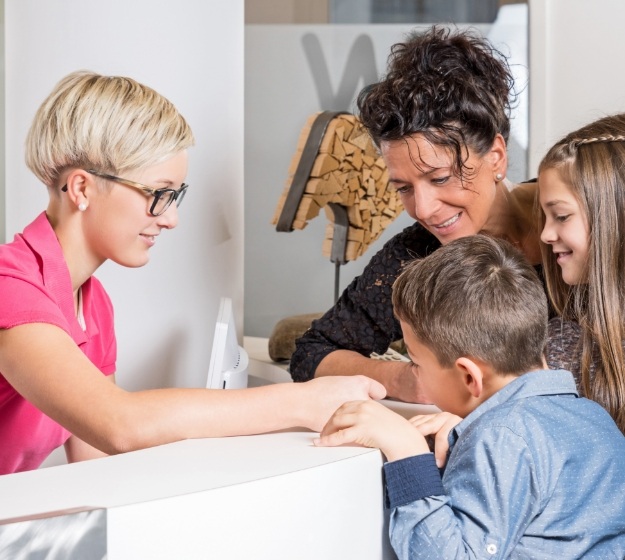 Mother and daughter talking to receptionist at front desk