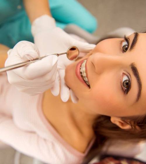 Young woman in orthodontic treatment chair smiling up at the camera