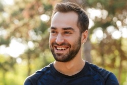 Man in dark blue tee shirt smiling outdoors