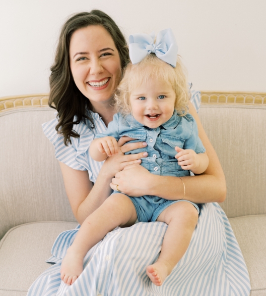 Doctor Hanson smiling while holding her baby daughter in her lap