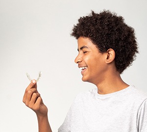 Teen holding an Invisalign aligner