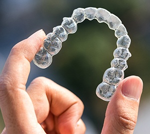 Hand holding an Invisalign aligner