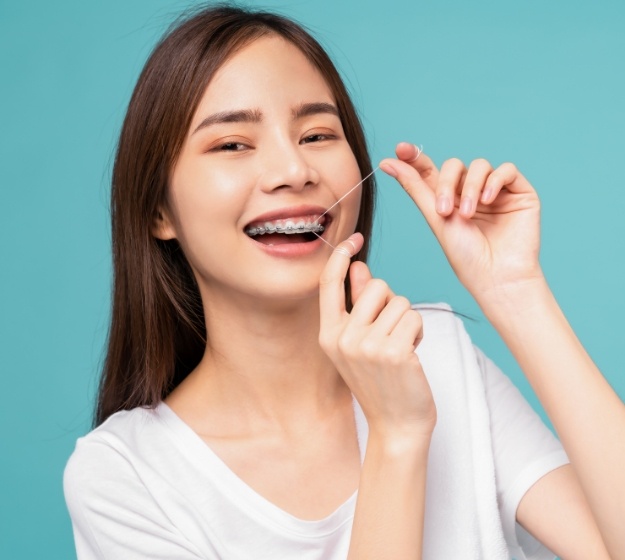 Young woman with braces flossing