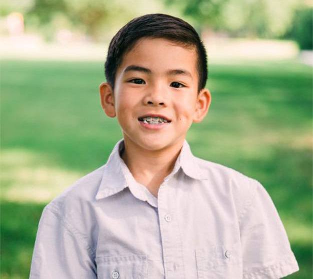 Young boy with braces smiling outdoors