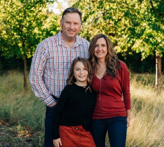 Family of three smiling outdoors