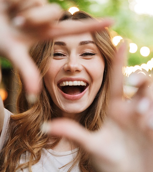 young woman framing her smile with fingers