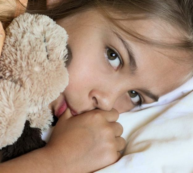 a child sucking on their thumb and lying in bed