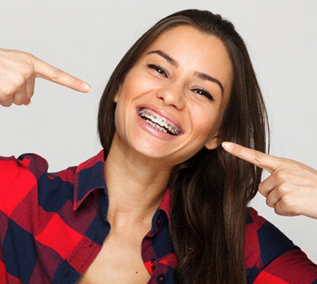 Smiling young woman pointing at her braces