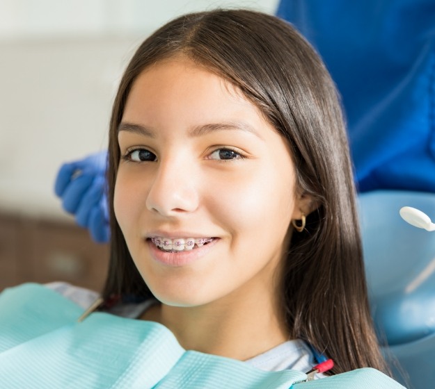 Teenage girl in dental chair smiling with traditional braces in Allen