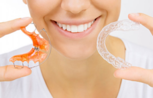 Close up of woman holding two types of retainers and smiling